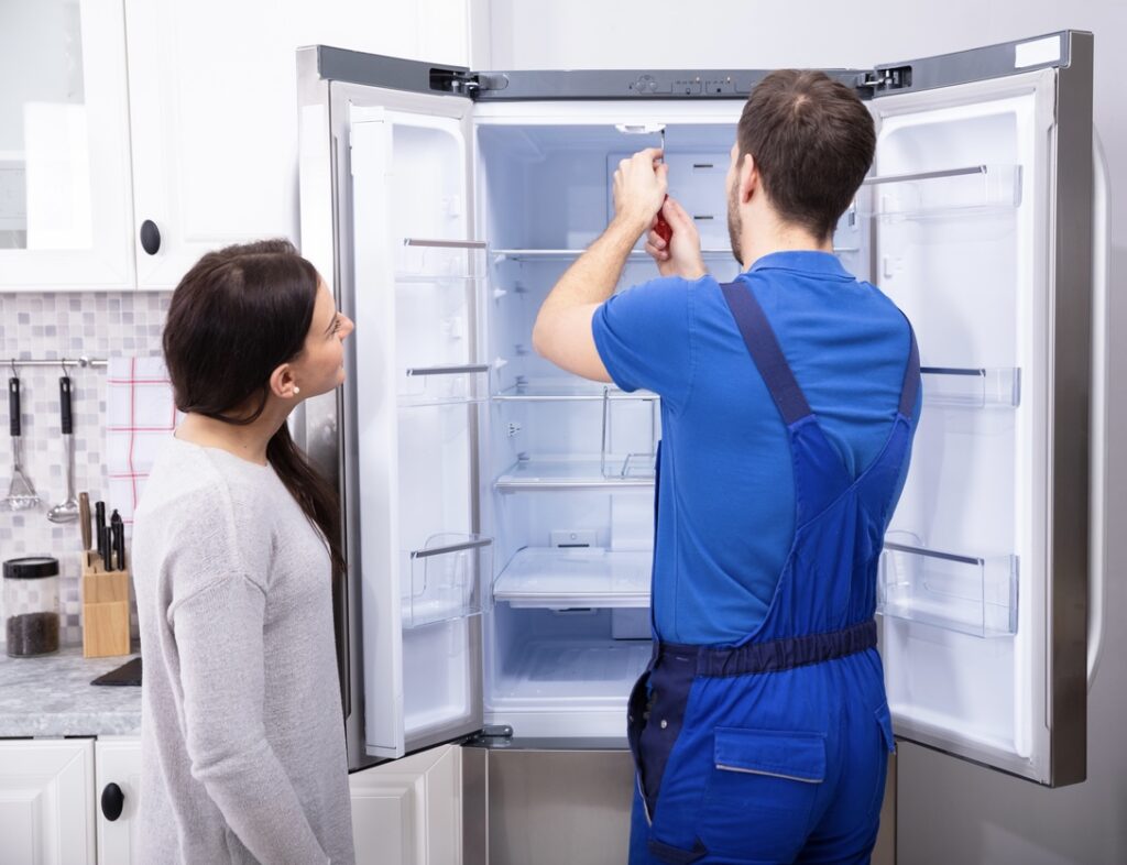 Repairman Fixing Refrigerator With Screwdriver